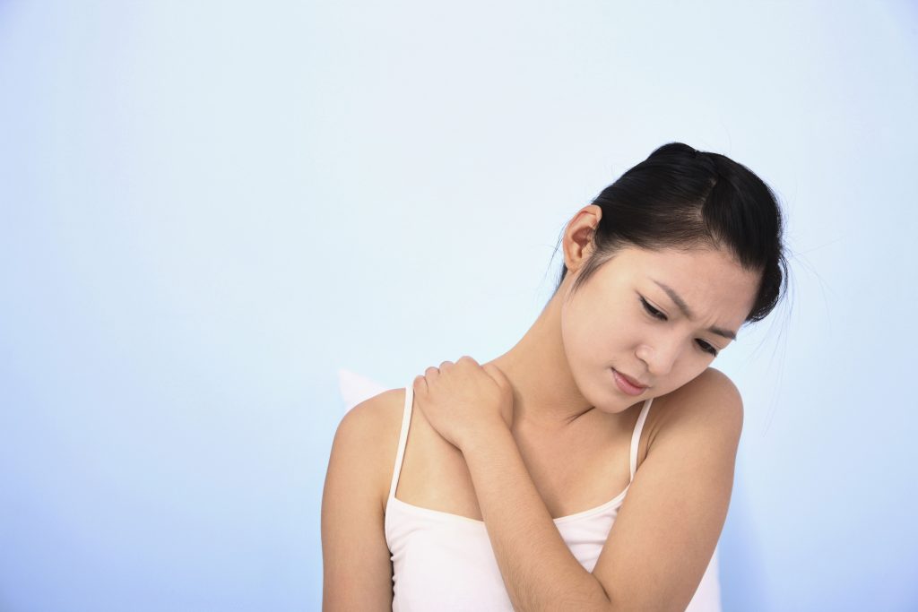 stressed woman rubbing her sore shoulder
