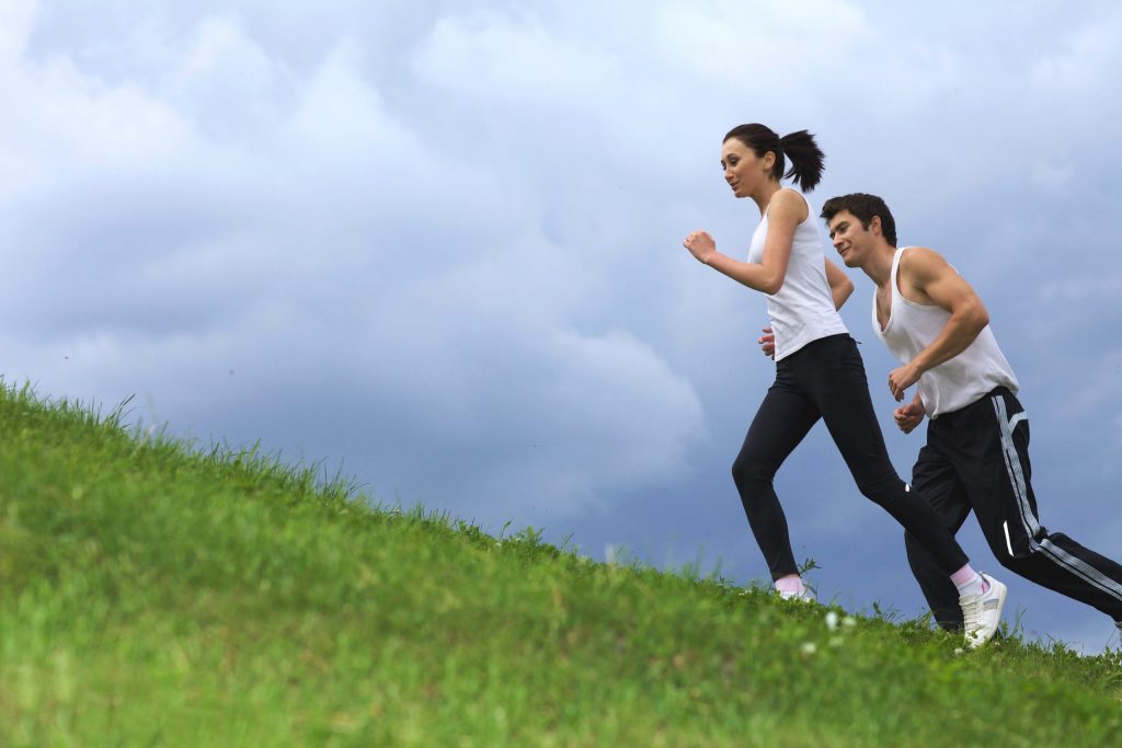 man and woman running up a grassy hill