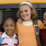 Students standing in front of a school bus