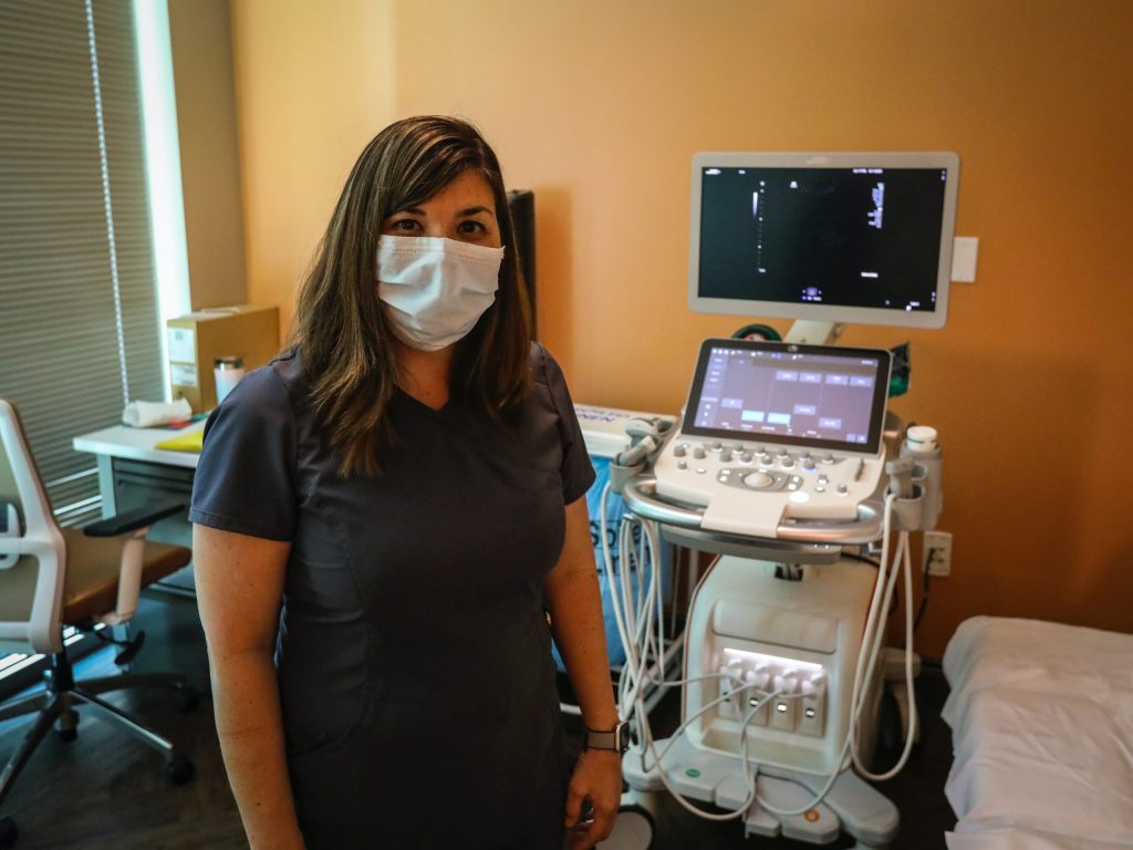 Sonographer standing next to an ultrasound machine