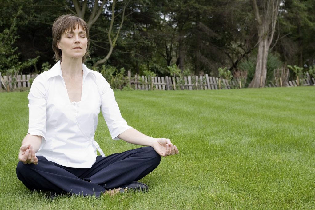 Woman meditating while sitting in the grass