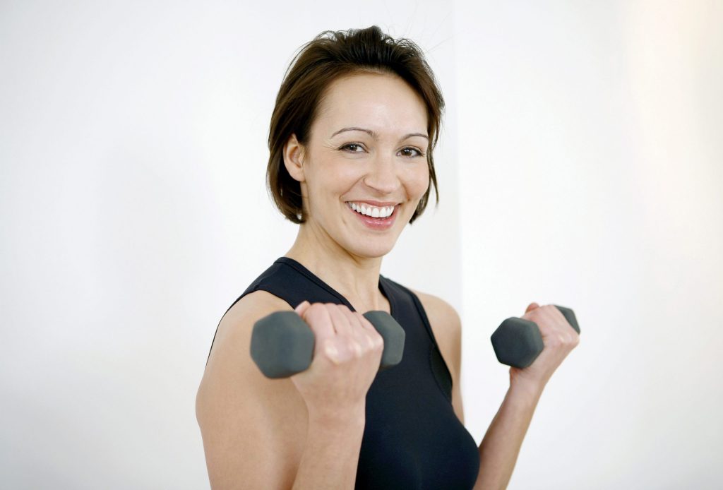 Woman smiling while lifting weights for exercise